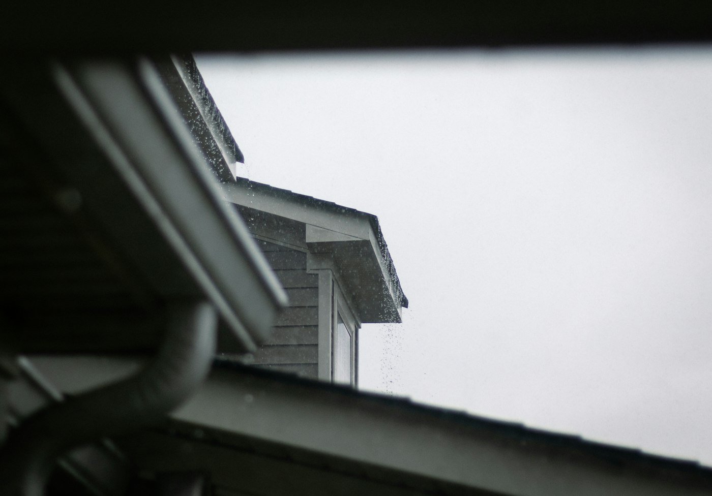 Rain streaming off a guttered roof edge
